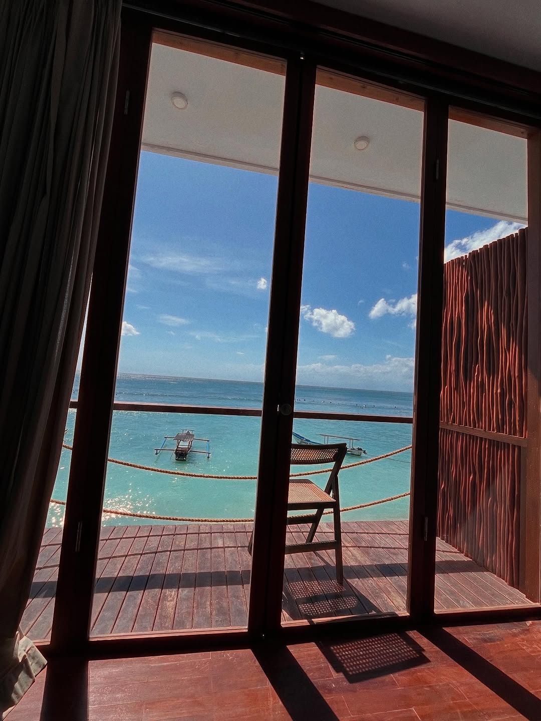A private deck chair overlooking turquoise water and traditional fishing boats at The Ohm