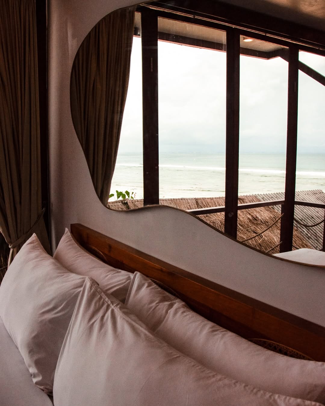 Ohm room pillows framed by an organic window looking at the waves