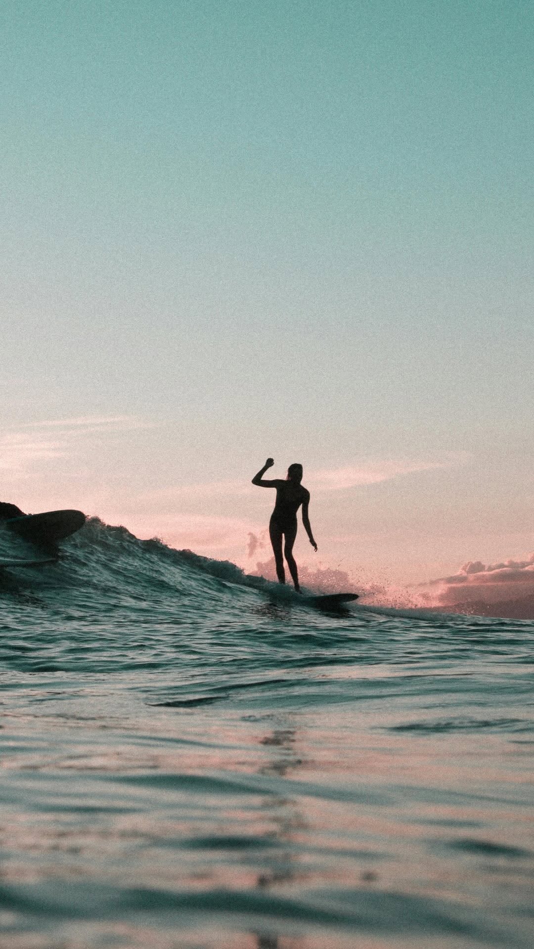 Surfer riding a wave at sunset near Thomas Beach
